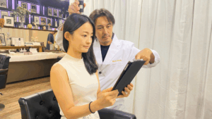 Manoukian麻布台の「再生育毛Manouシステム」について、専門家が女性のお客様にタブレットを使ってカウンセリングを行う様子